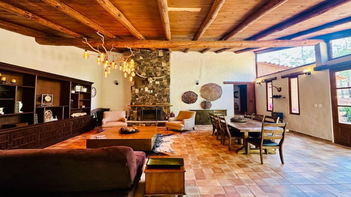 Sala con chimenea de piedra y vigas de madera